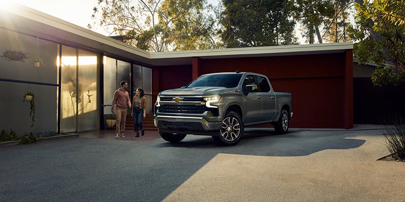 Couple standing next to a CHevy Silverado parked in their driveway